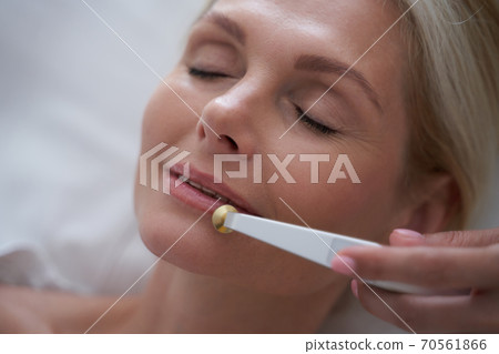 Blonde lady with closed eyes during cosmetic procedures 70561866