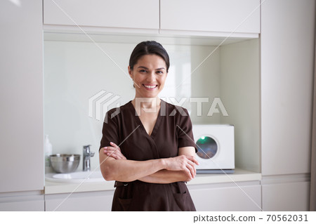 Smiling pretty young cosmetologist standing in beauty clinic Smiling pretty young cosmetologist standing in beauty clinic 70562031