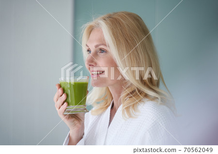Happy blonde woman standing with healthy drink 70562049