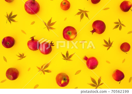 Pattern of pomegranate fuits with fall leaves isolated on bright yellow background. Flat lay 70562199