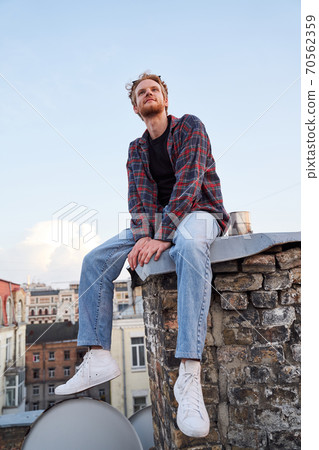 Cheerful young man on roof in solitude 70562359