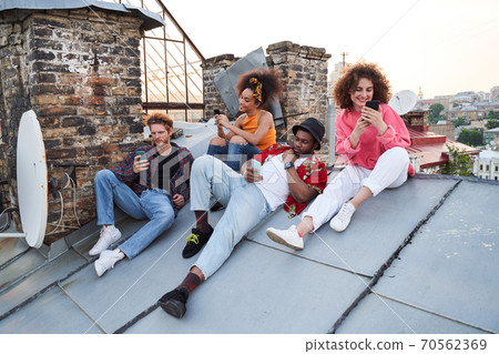 Jolly young people surfing internet together outdoors Jolly young people surfing internet together outdoors 70562369
