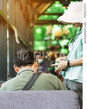 Back view of Asian male customer sit in waiting social distance queue for take away drink in coffee shop. New normal lifestyle concept. Back view of Asian male customer sit in waiting social distance queue for take away drink in coffee shop. New normal lifestyle concept. 70562473