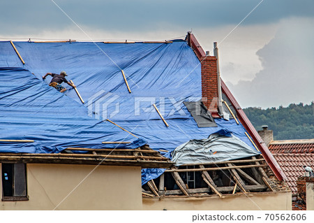 The roofer works on roof when is rain. The roofer works on roof when is rain. 70562606