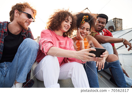 Cheerful friends using smartphone on urban roof 70562817