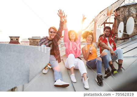 Two happy couples with bottles of drinks outdoors Two happy couples with bottles of drinks outdoors 70562819