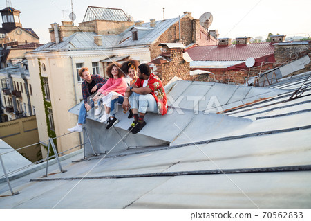 Young company on roof of old urban house 70562833