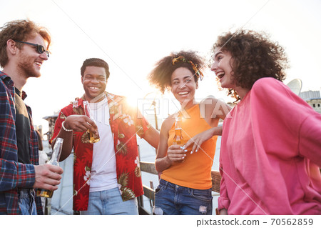 Happy friends celebrating with beer at sunset Happy friends celebrating with beer at sunset 70562859