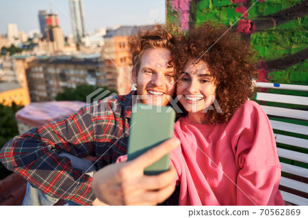 Happy young couple taking selfie while dating on roof Happy young couple taking selfie while dating on roof 70562869
