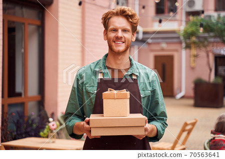 Smiling man holding gift boxes Smiling man holding gift boxes 70563641