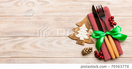 Top view of fork and knife tied up with ribbon on napkin on wooden background. Christmas decorations and New Year tree. Banner Happy holiday concept with empty space for your design 70563778