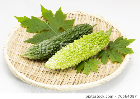Bitter melon with leaves placed on a colander 70564087