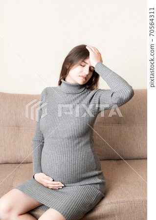 Young pregnant woman suffering from headache on sofa in home. Maternity healthcare concept Young pregnant woman suffering from headache on sofa in home. Maternity healthcare concept 70564311