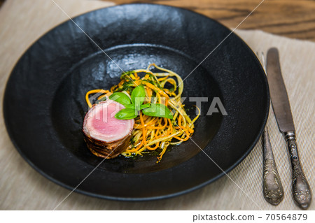 Tenderloin wrapped in bacon with zucchini carrot noodles 70564879