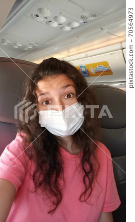 A girl in a mask makes a selfie in the cabin of the plane. flights under the new rules coronavirus A girl in a mask makes a selfie in the cabin of the plane. flights under the new rules coronavirus 70564973