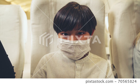 Traveler wearing face mask while traveling on commercial airplane . Traveler wearing face mask while traveling on commercial airplane . 70565824