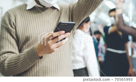 Traveler wearing face mask while using mobile phone on public train Traveler wearing face mask while using mobile phone on public train 70565993