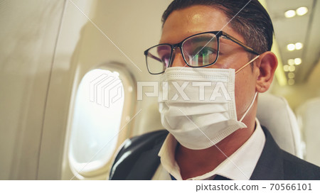 Traveler wearing face mask while traveling on commercial airplane . 70566101