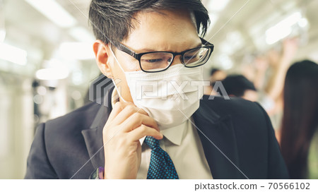Young man wearing face mask travels on crowded subway train Young man wearing face mask travels on crowded subway train 70566102