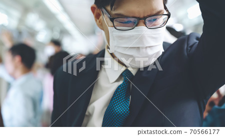 Young man wearing face mask travels on crowded subway train 70566177