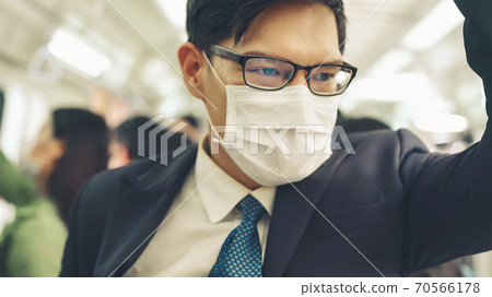 Young man wearing face mask travels on crowded subway train 70566178