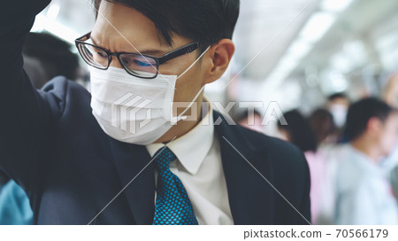 Young man wearing face mask travels on crowded subway train 70566179
