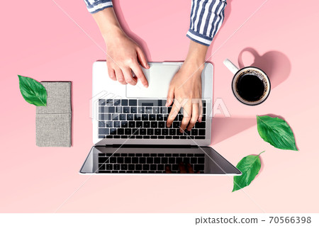 Person using a laptop computer with green leaves 70566398