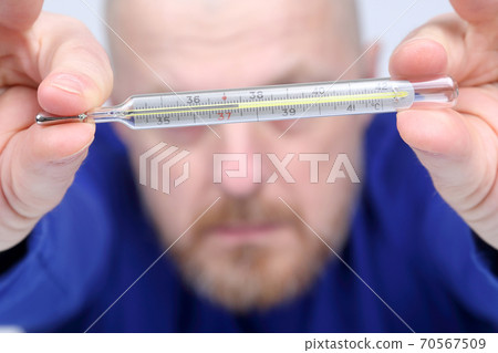 man shows a thermometer with a high temperature 70567509