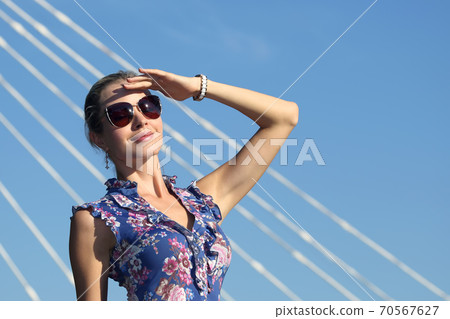 beautiful young girl in sunglasses with her hand raised looking at the sun. beautiful young girl in sunglasses with her hand raised looking at the sun. 70567627