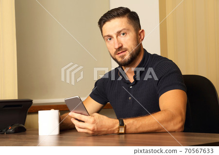 business man with cup and cell phone in hand sitting at the table business man with cup and cell phone in hand sitting at the table 70567633