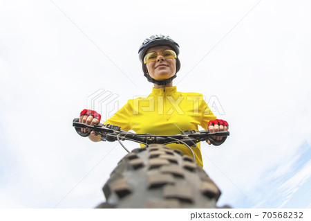 Beautiful girl cyclist looking forward to the wheel of the bike. Sports and recreation.  70568232