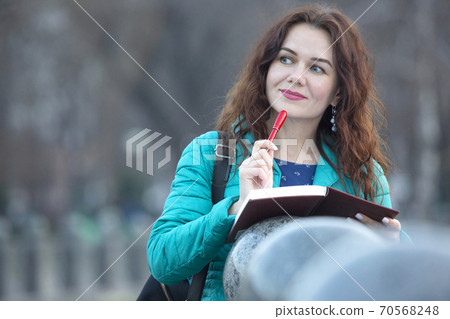 Portrait of a beautiful smiling girl with a red pen in her hand Portrait of a beautiful smiling girl with a red pen in her hand 70568248