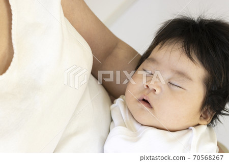 A mother in her thirties and a baby hugged and sleeping 70568267