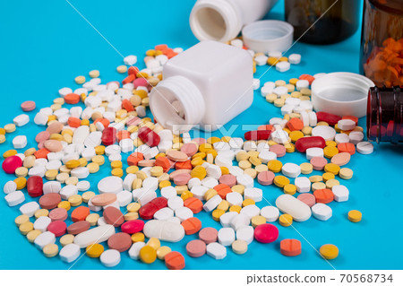 Medical pills and tablets spilling out of a drug bottle on blue background 70568734