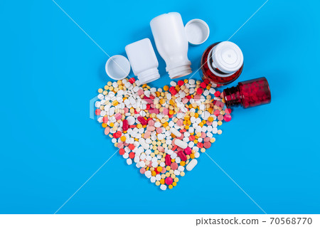 Medical pills and tablets spilling out of a drug bottle on blue background 70568770