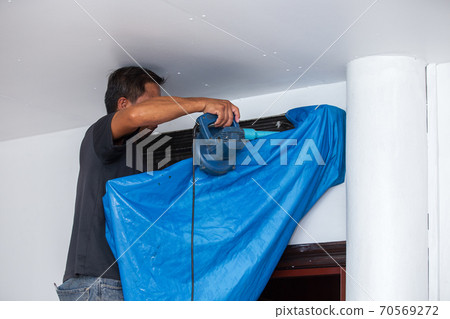 Male technician cleaning air conditioner. 70569272
