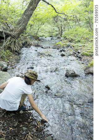Outdoor, camping, trekking image Elementary school girl touching the water of the river 70569935
