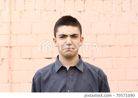 happy teenager boy grimace wink closeup portrait on white wall background 70571090