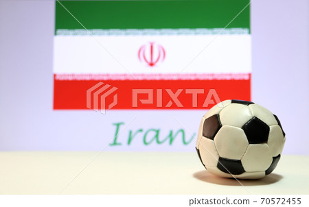 Small football on the white floor and Iranian nation flag with the text of Iran background. Small football on the white floor and Iranian nation flag with the text of Iran background. 70572455