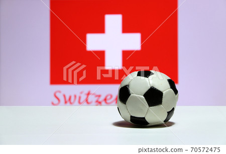 Small football on the white floor and Swiss nation flag with the text of Switzerland background. Small football on the white floor and Swiss nation flag with the text of Switzerland background. 70572475