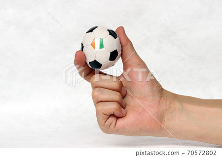 Mini ball of football in hand and one black point of football is Ivory Coast flag 70572802