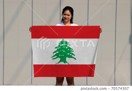pretty lady holding Lebanon flag in her hands on grey background. 70574307