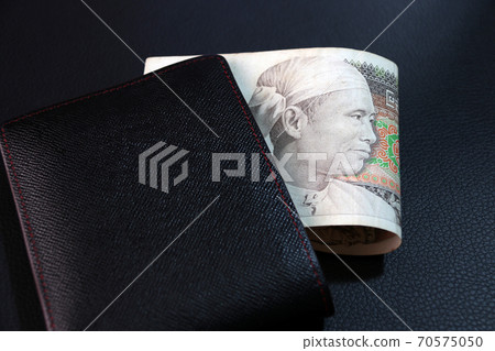 Seventy five of banknote currency Myanmar kyats with black wallet on the black floor. Seventy five of banknote currency Myanmar kyats with black wallet on the black floor. 70575050