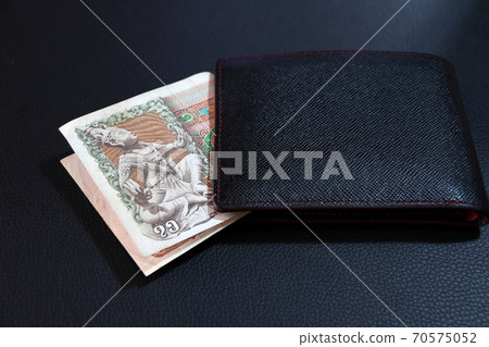 Seventy five of banknote currency Myanmar kyats with black wallet on the black floor. Seventy five of banknote currency Myanmar kyats with black wallet on the black floor. 70575052