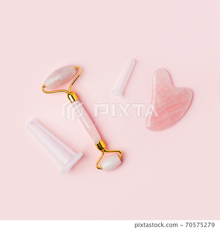Massage quartz roller, stone, tools for the face of pink natural nephritis. Skin care facial massage and relaxation concept. Gua Sha massage tools. Anti age and lifting at home. 70575279