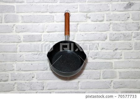 Boil pot with long wooden handle hanging on the brick pattern wall. Boil pot with long wooden handle hanging on the brick pattern wall. 70577733