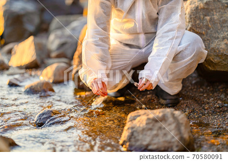 Close-up of researcher collecting water sample at seashore Close-up of researcher collecting water sample at seashore 70580091