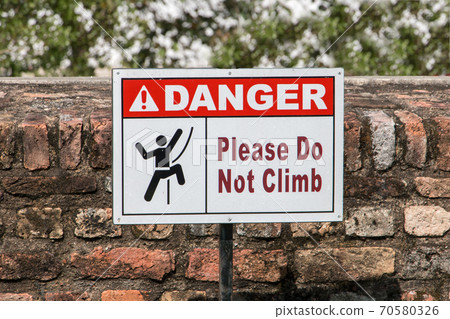 Signs with a ban on climbing the brick wall. 70580326