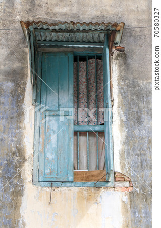 An open window with grilles and a sheet metal roof in the facade of an old house, Penang, Malaysia. 70580327