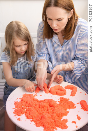 mother and daughter playing with kinetic sand. 70583167